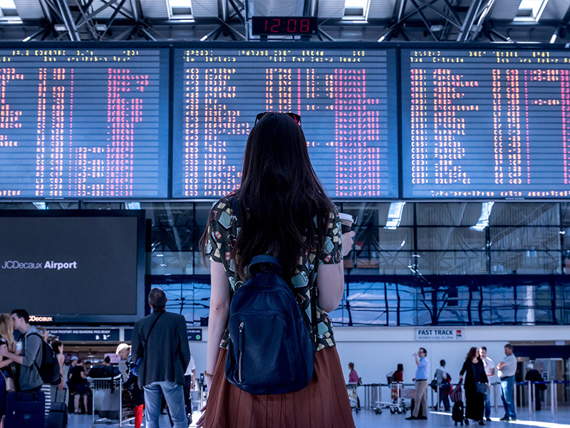 Girl standing in an airport looking at the departure board