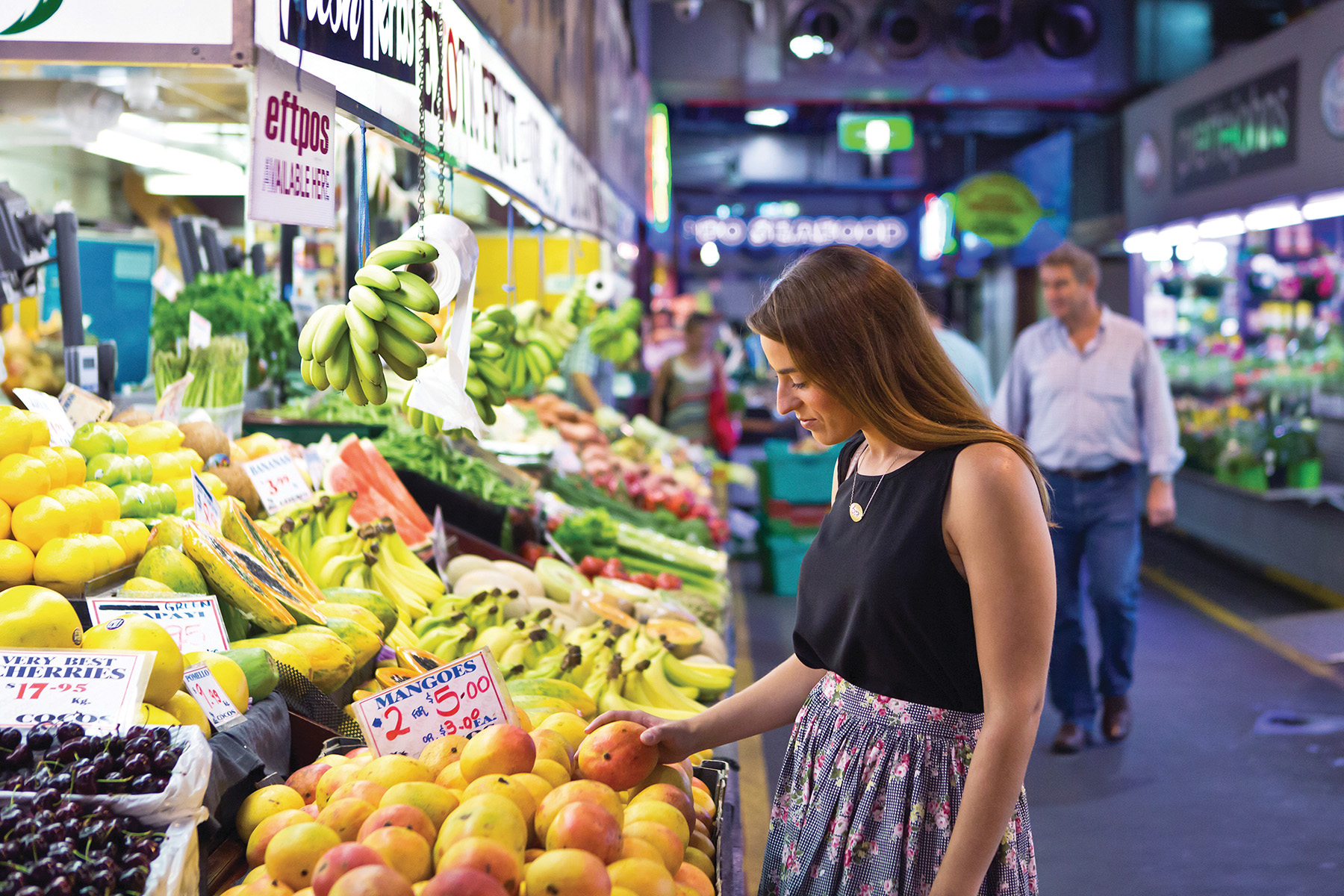 a student choosing mangoes at the Adelaide Central Market